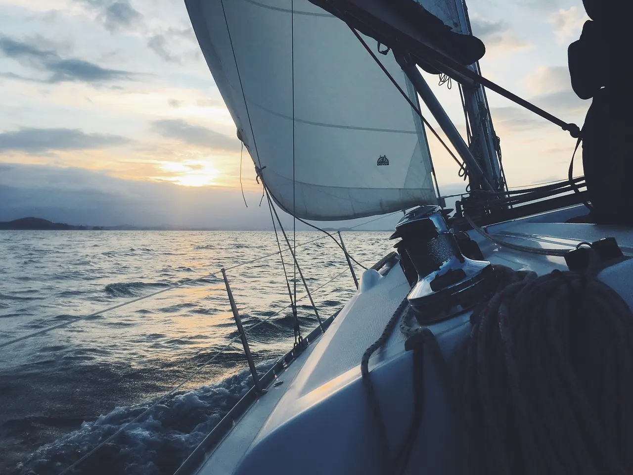 A sailing yacht under way at sunset, seen from the deck